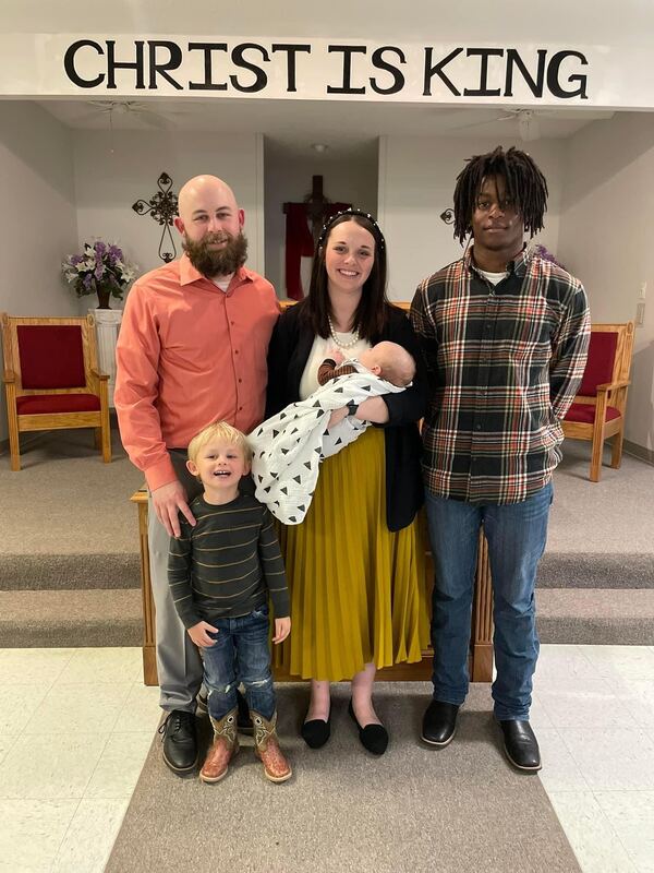 Pastor Jacob Robinson and his wife Taylor with their three children in front of the pulpit beneath a “Christ is King” sign.